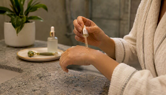 Hands applying layered water-based serum and facial oil