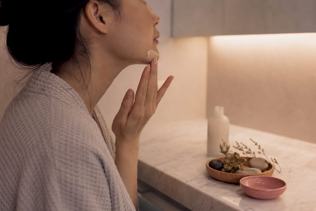 Hands applying sake lees serum to face