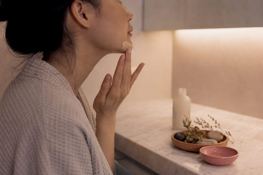 Hands applying sake lees serum to face
