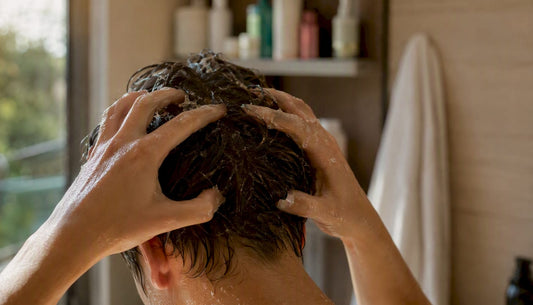 Hands applying Korean scalp exfoliant in bathroom